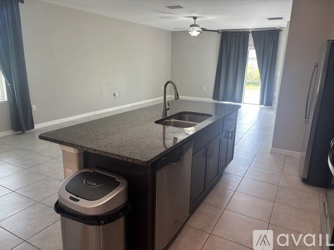 A kitchen with a sink and a trash can.