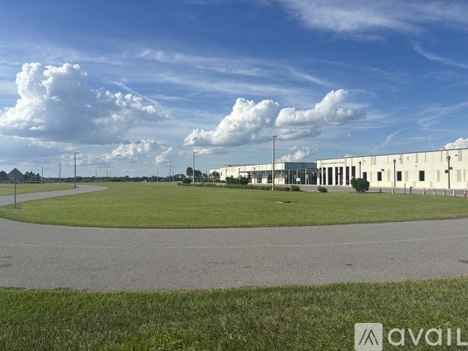 A large white building with a grassy field in front and a clear blue sky above.