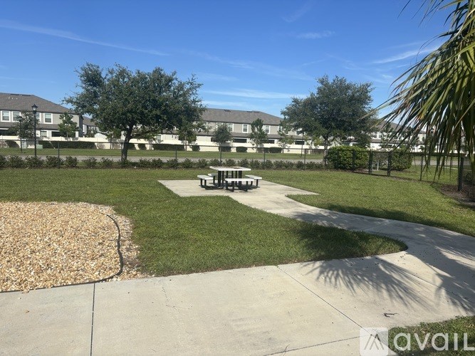 A sunny day at a park with a bench and a playground.