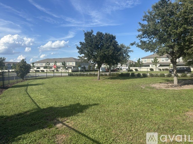 A grassy field with trees and a building in the background.