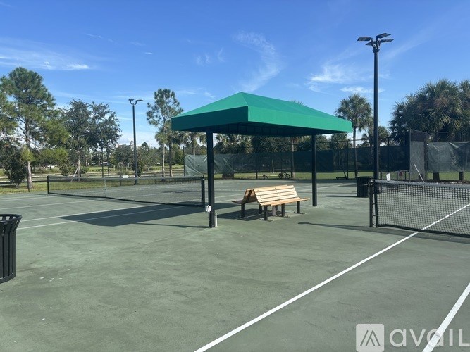 A tennis court with a green canopy and a bench.