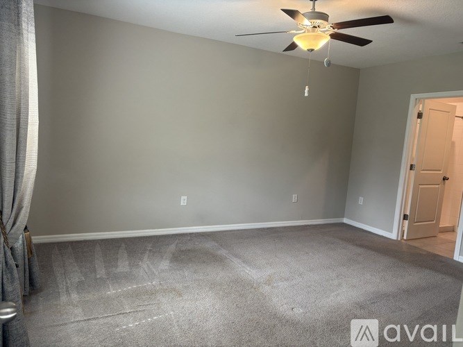 A room with a ceiling fan and a carpeted floor.