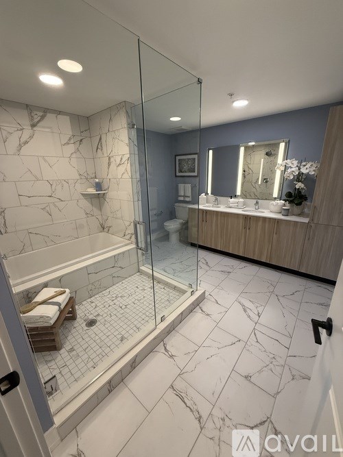 A bathroom with marble tiles and a glass shower stall.