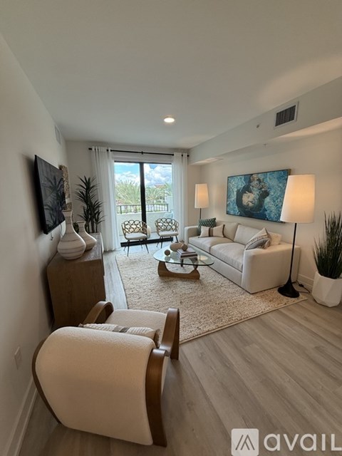 A living room with a white couch, a wooden coffee table, and a painting on the wall.