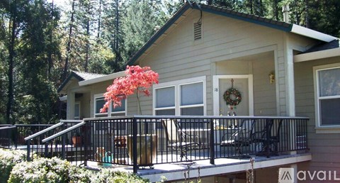 A house with a balcony and a tree in front of it.