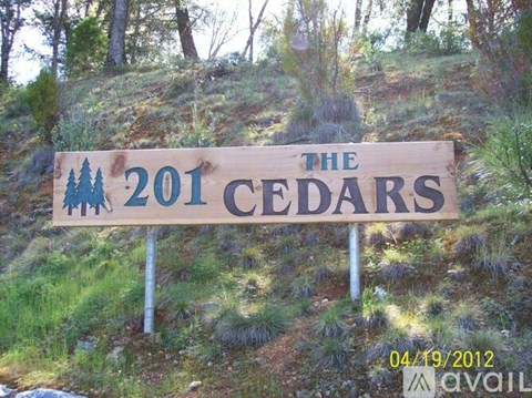 A wooden sign that says "The 201 Cedars" is in front of a hill.