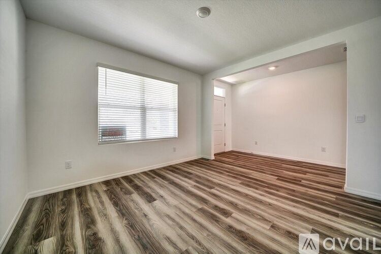 A room with wooden flooring and a window with blinds.