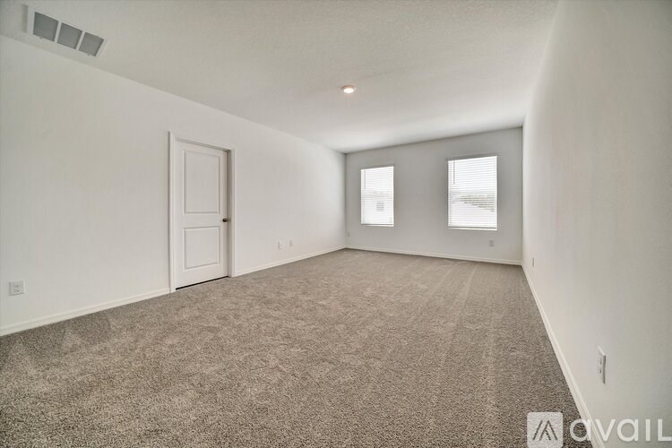 A room with carpeted floor and two windows.