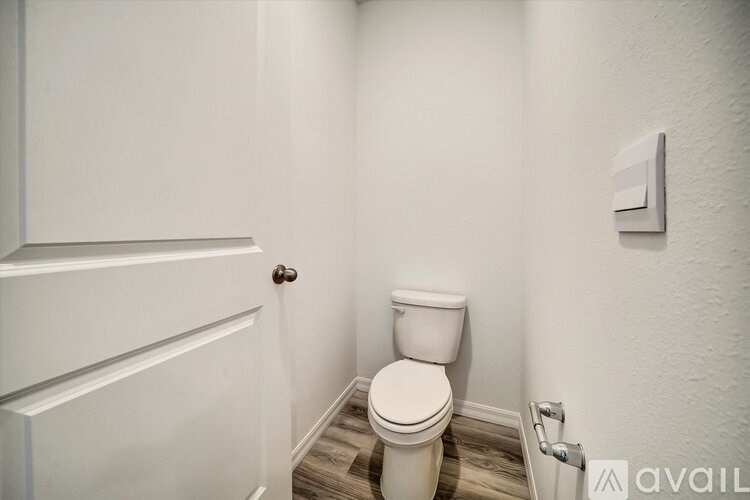 A white toilet in a small bathroom with a door on the left.
