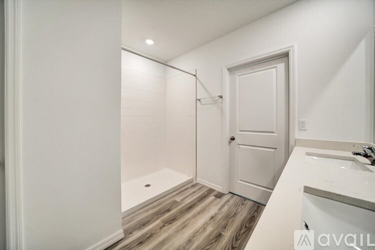 A white bathroom with a walk-in shower and a white door.