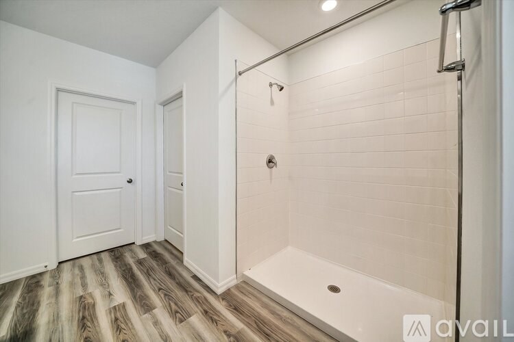 A bathroom with a white door and a white tiled shower.