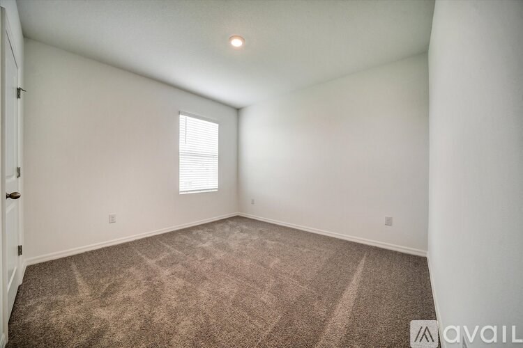 A room with a carpeted floor and a window with blinds.