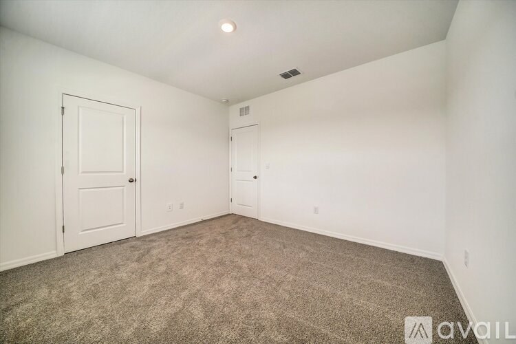 A room with carpeted floor and two doors.