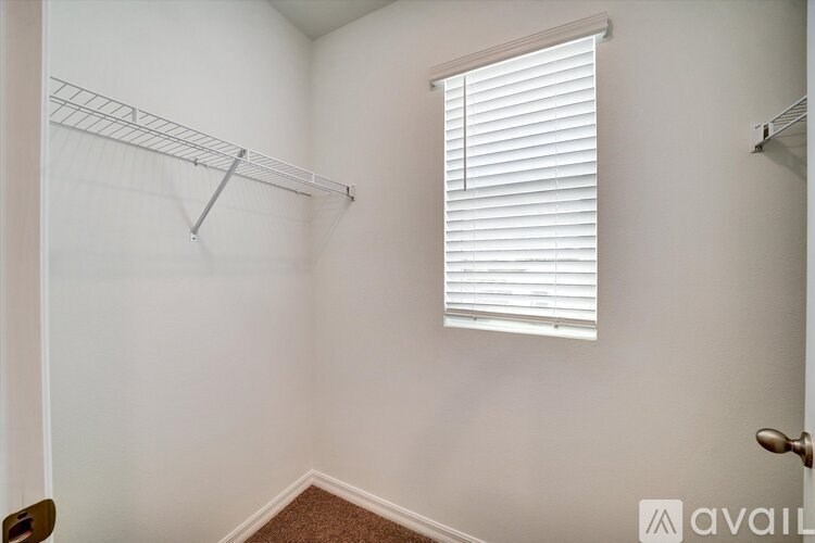 A white wall with a metal rack and a window with blinds.
