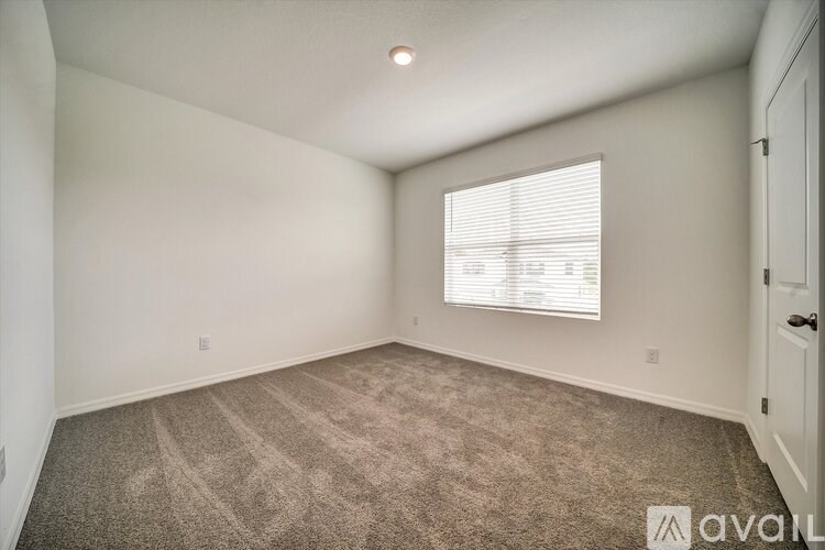 A room with a carpeted floor and a window with blinds.