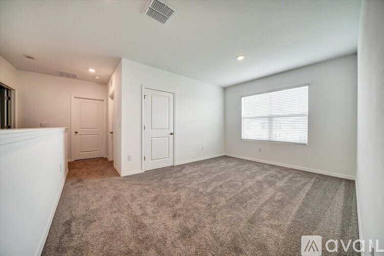 A room with a carpeted floor and a window with blinds.