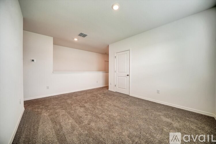 A room with a carpeted floor and a door is available for rent.