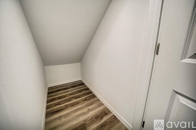 A hallway with wooden flooring and white walls.