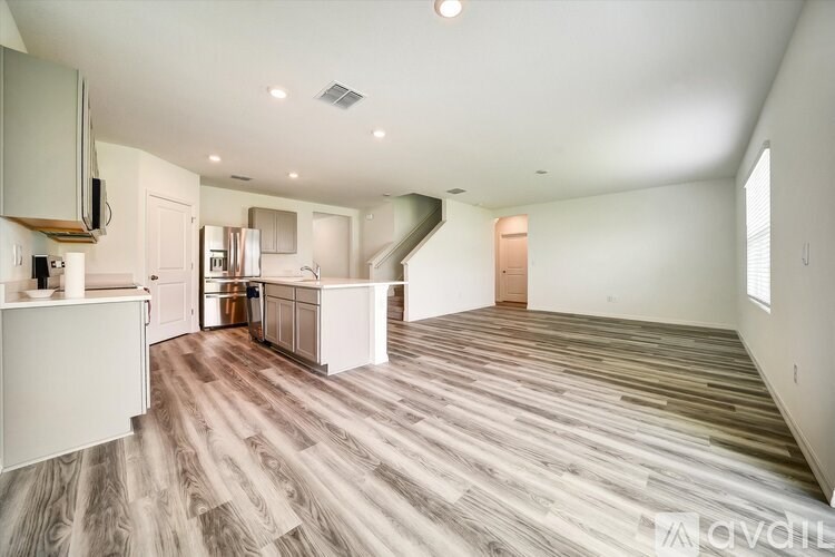 A spacious kitchen with white cabinets and a wooden floor.