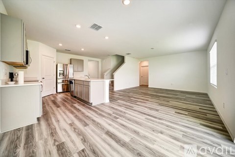 A spacious kitchen with white cabinets and a wooden floor.