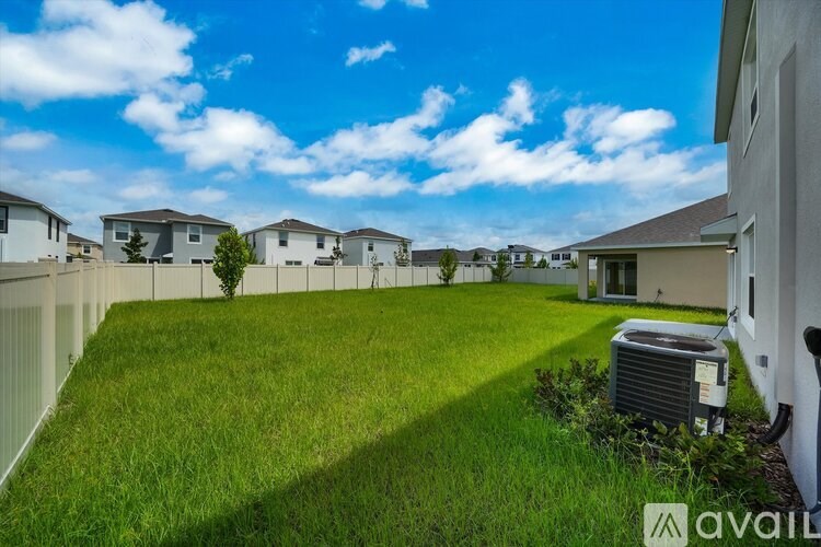 A grassy backyard with a fence and houses in the background.