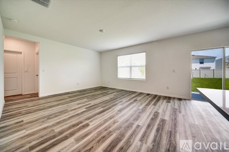A spacious room with wooden flooring and a large window.