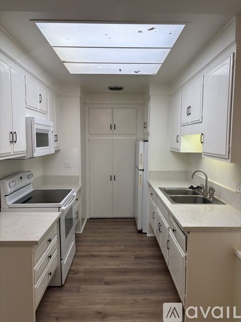 A kitchen with white cabinets and a wooden floor.