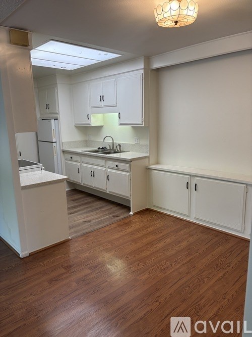 A kitchen with white cabinets and a wooden floor.