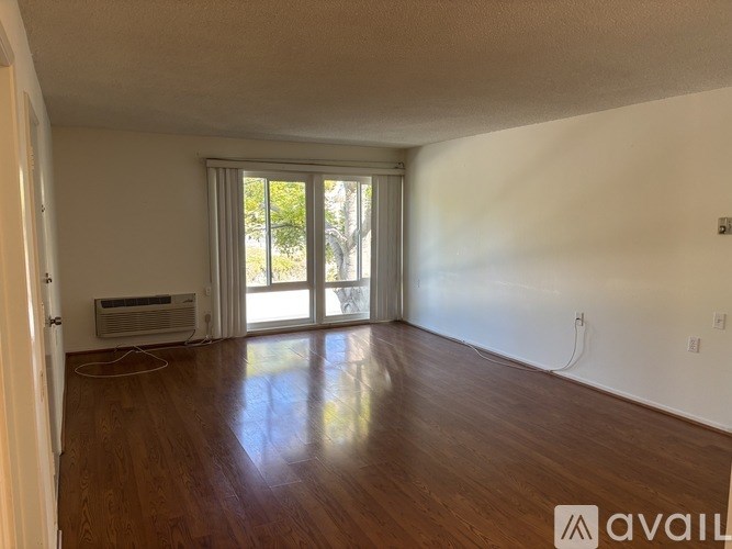 A room with wooden floors and a sliding glass door leading outside.
