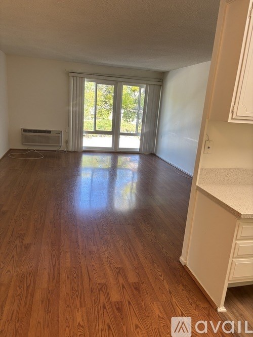 A room with wooden floors and a window with blinds.