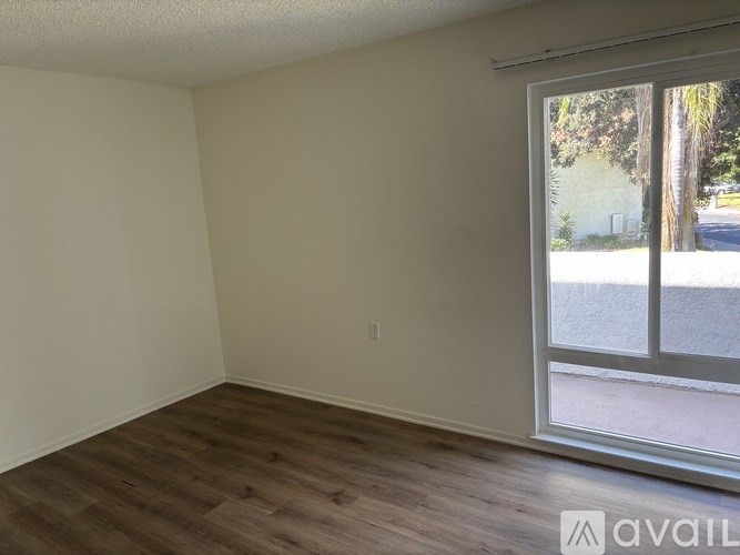 Empty room with wooden flooring and a sliding glass door.
