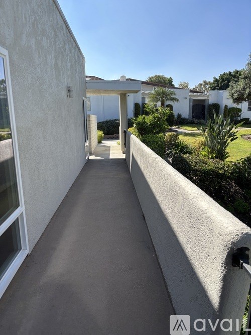 A long concrete walkway leads to a white house.