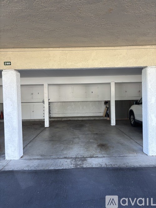 A car is parked in a garage with a white column on the left.