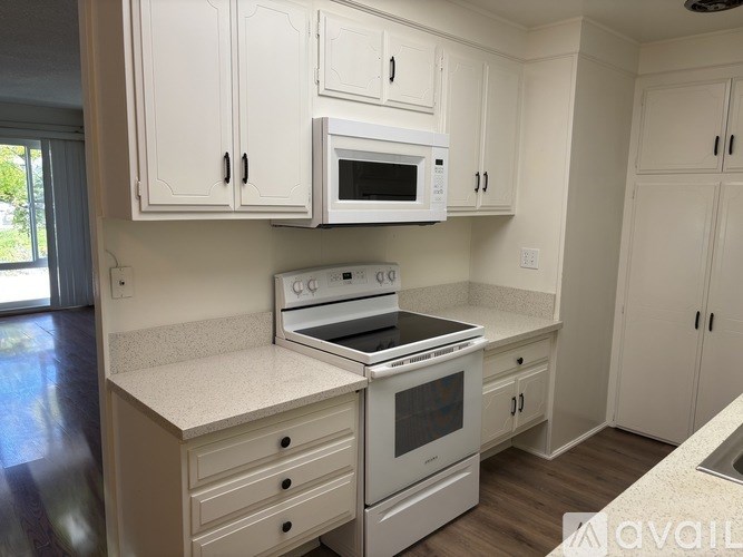 A kitchen with white cabinets and appliances.
