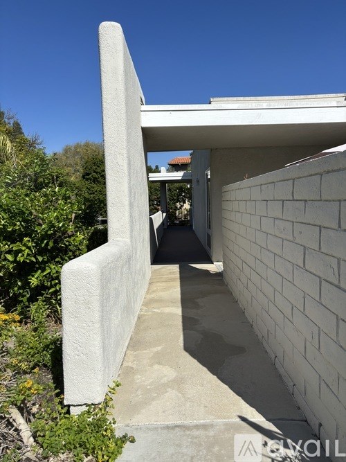 A white concrete structure stands in front of a white brick wall.