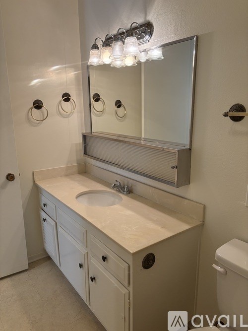 A bathroom with a sink, mirror, and toilet.