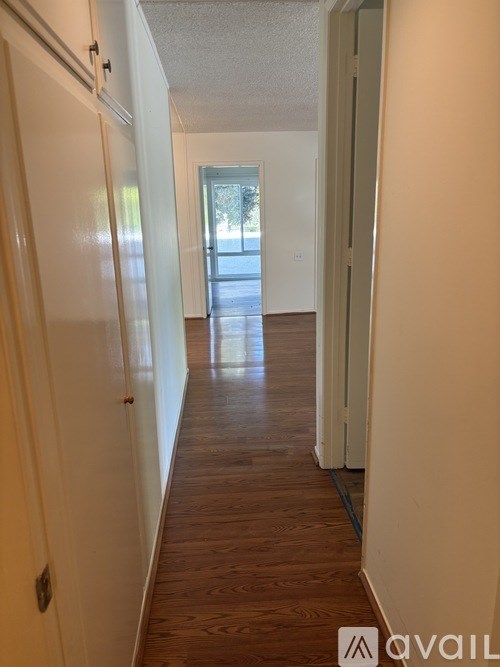 A long hallway with wood floors and white walls.