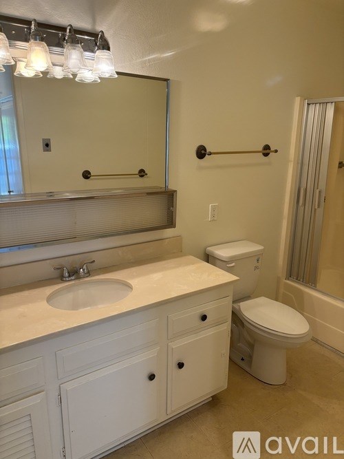 A bathroom with a toilet, sink, and mirror.