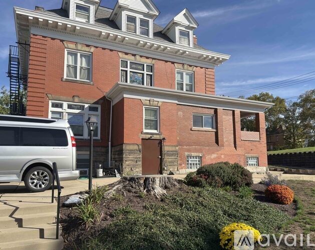A red brick house with a silver van parked in front.