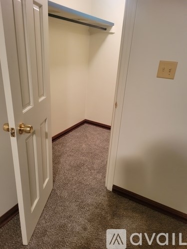 A white door with a gold handle is open to a hallway.