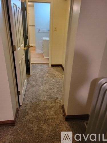 A hallway with a carpeted floor and a door on the left.
