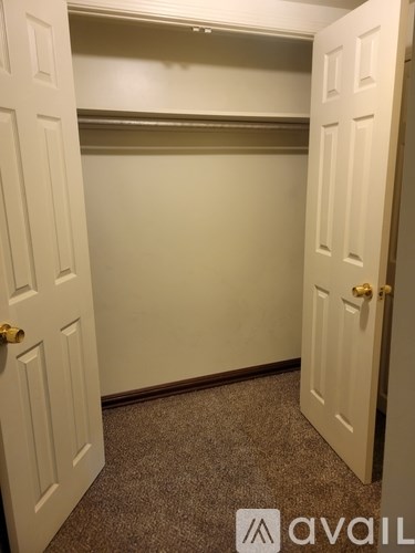 A white door with a gold handle is open to a room with a carpeted floor.