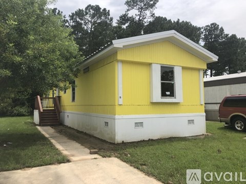 A yellow house with a white trim and a small porch.