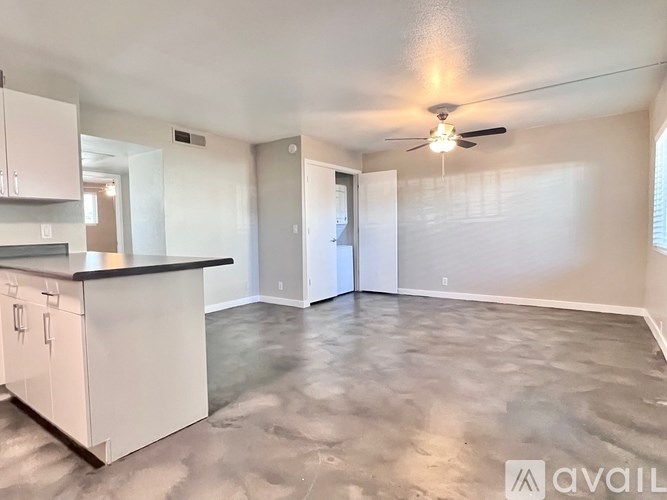 A spacious living room with a kitchenette and a ceiling fan.