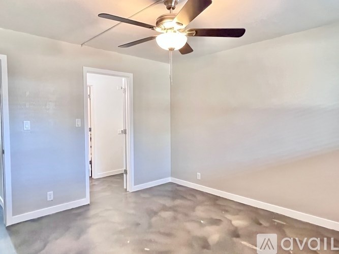 A room with a ceiling fan and a door.