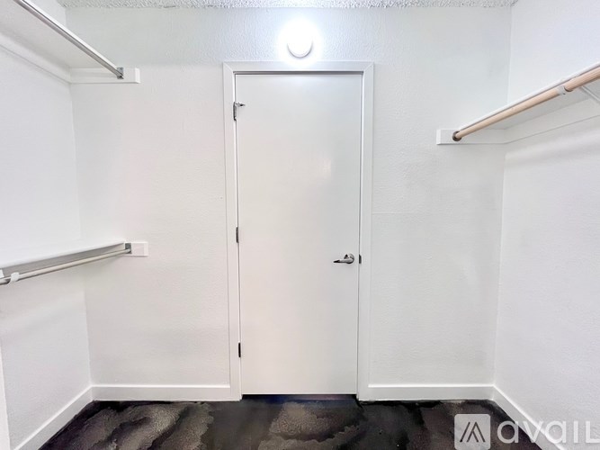 A white door is closed in a room with white walls.