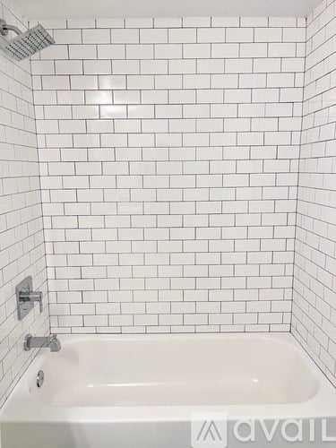 A white bathtub with a shower head above it.