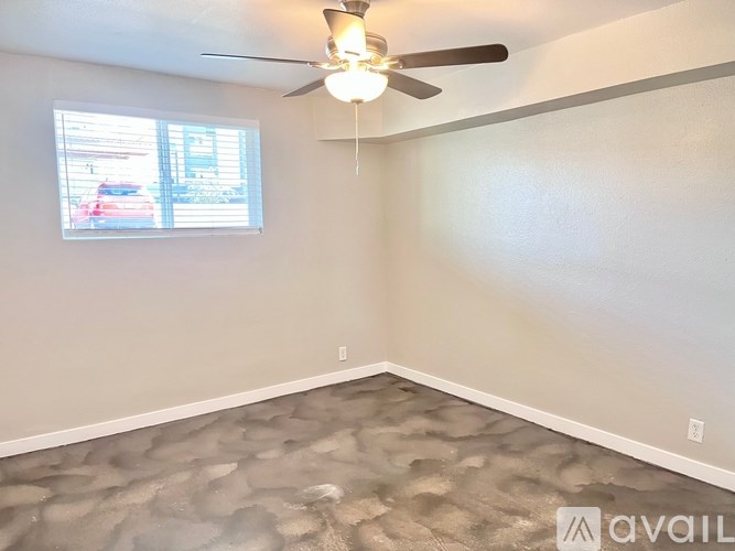 A room with a ceiling fan and a window with blinds.