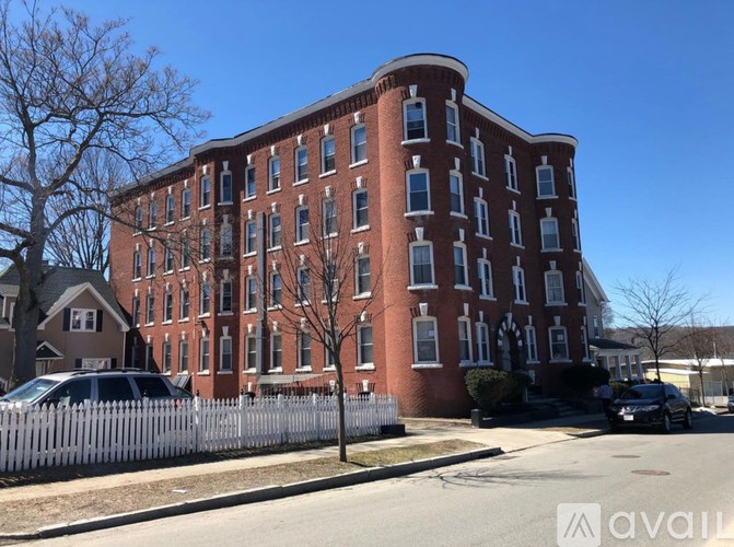 A large red brick building with a white picket fence in front.