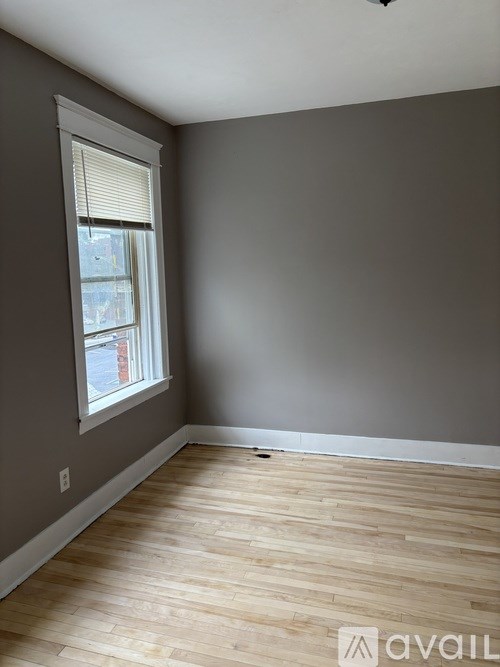 A room with wooden flooring and a window with blinds.